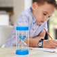 A child sitting at a table with a blue and clear sand timer.