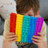 A child holding a multicolored jumbo bubble pop fidget toy.