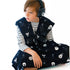 A child wearing black with a pattern of light bulbs and other sensory items, including a denim sack with the product name &