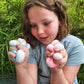 A child holding two pocket-sized sensory stress balls in blue and pink colors.