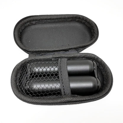 A hand holding a silver-colored metal roller toy with a child lying on a couch in the background.