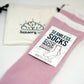 A two-pack of pink seamless socks with a rose design and a white band, labeled &