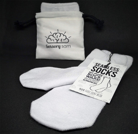 A pair of white, seamless socks made from bamboo, displayed next to their packaging which reads &