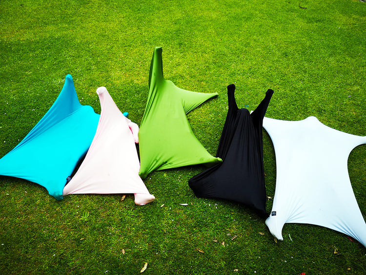 A collection of sensory body socks laid out on grass, with colors including blue, green, black, white, and red.