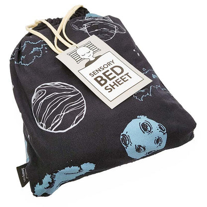 A black sensory bed sheet with space-themed prints, packaged with a label that reads &