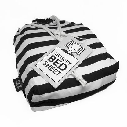 Black and white striped sensory bed sheet with tags, designed for use on a bed.