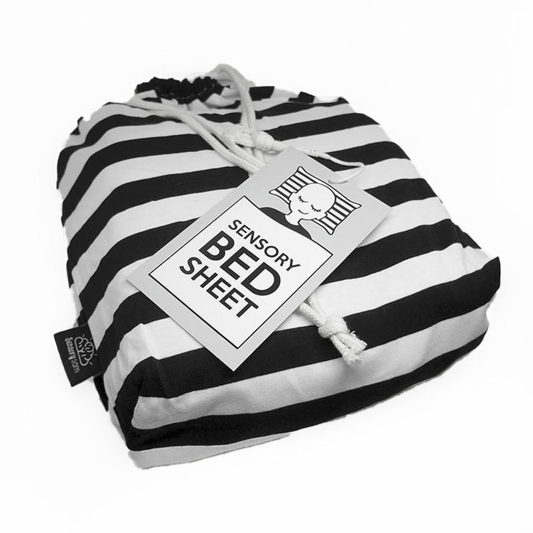 Black and white striped sensory bed sheet with tags, designed for use on a bed.