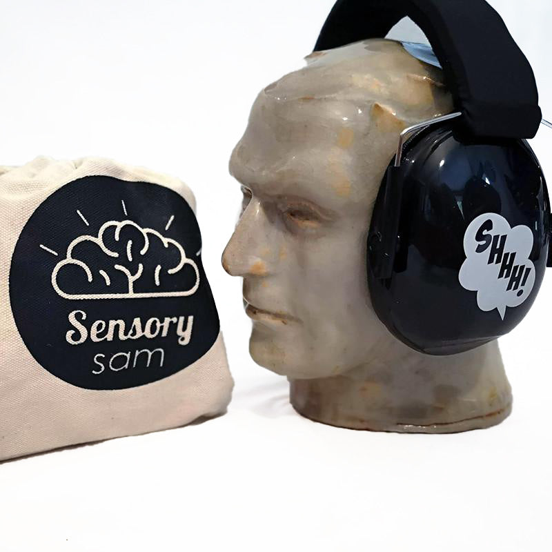 A pair of black ear muffs designed for children, displayed on a mannequin head, next to a bag with the logo &