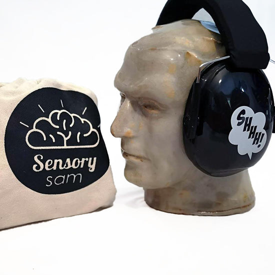 A pair of black ear muffs designed for children, displayed on a mannequin head, next to a bag with the logo &