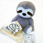 A weighted plush toy sloth with a white label, sitting against a white background.