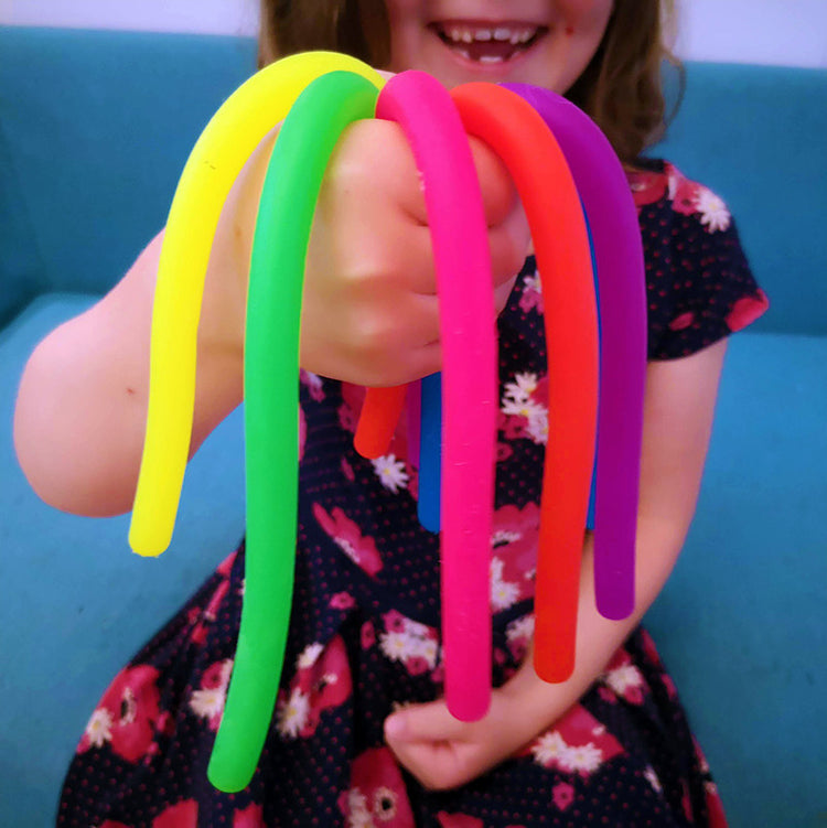 A child holding colorful stretchy stress strings in various colors including yellow, pink, purple, green, blue, and orange.