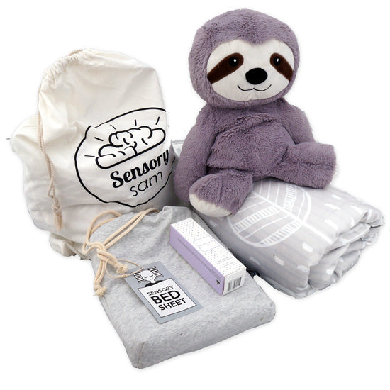 A collection of sleep aid products including a grey weighted blanket, a grey sensory sheet, a plush sloth toy, a pillow, and a drawstring bag with the Sensory Saint logo.