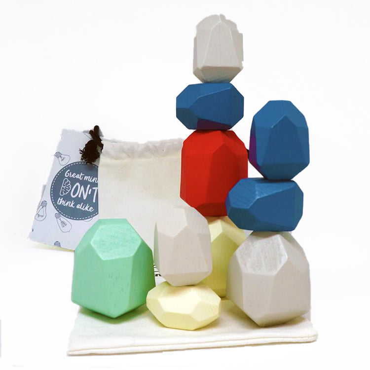 A collection of colorful wooden balance stones of various geometric shapes stacked together, with a cotton drawstring bag behind them.